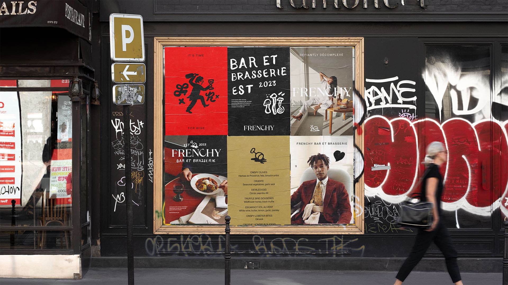 Six Frenchy posters glued to a grafitti covered wall and framed by one large frame on the streets of Toronto with pedestrians walking by.