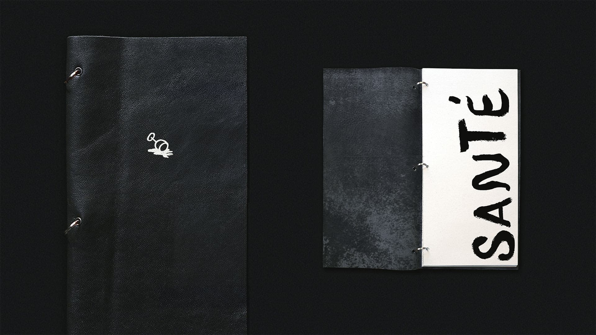 A black and white Frenchy menu, reading "santé" on one of the pages, and with the Frenchy spilling wineglass illustration on the cover. 