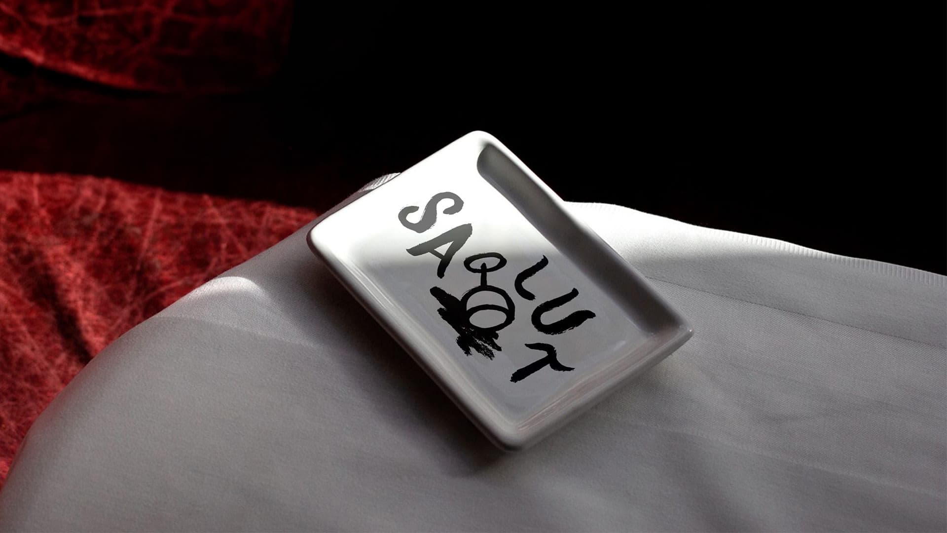 A tip tray that reads "salut" with the Frenchy tipped over wine glass illustration.
