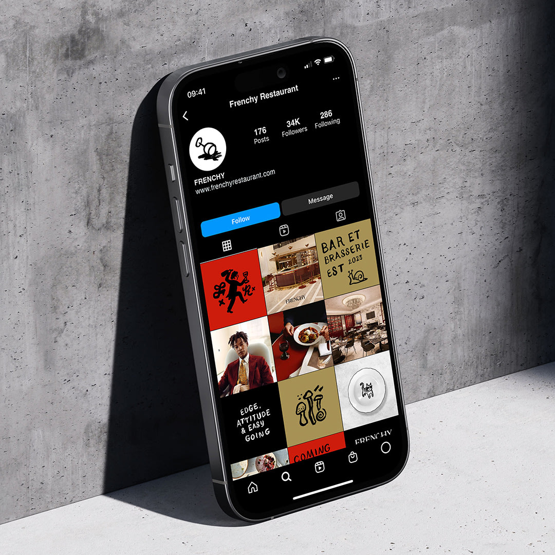A phone leaning against a concrete wall, displaying Frenchy's instagram grid.